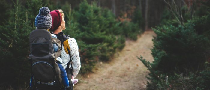woman and child hiking down a pine path